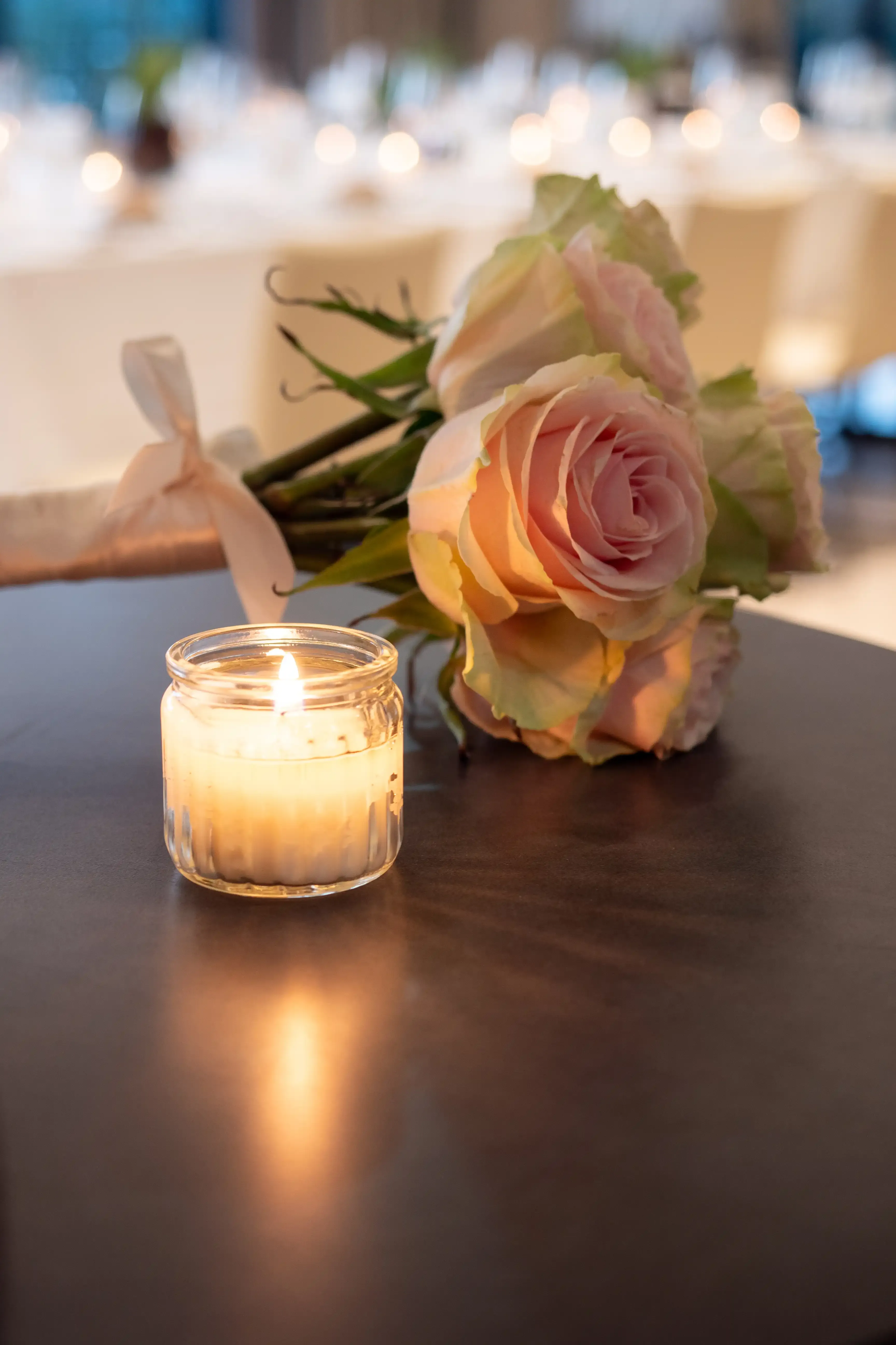 Enquadramento elegante do bouquet de flores ao pé de uma vela numa mesa